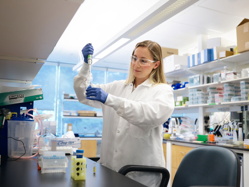 Woman using lab equipment in a lab setting studying cancer immunotherapy options