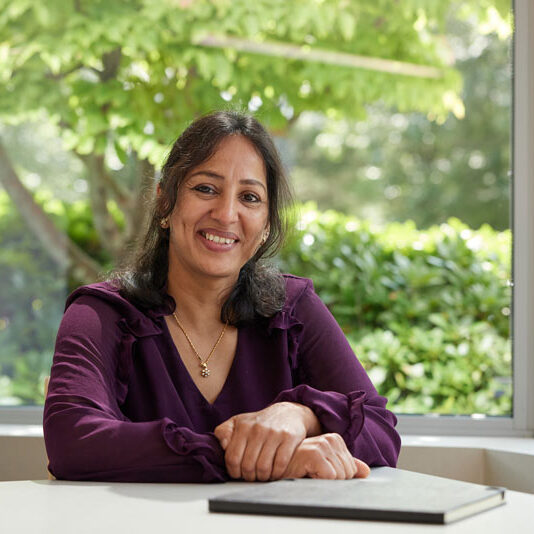 Mural Oncology immunotherapy employee sitting at desk smiling and folded hands