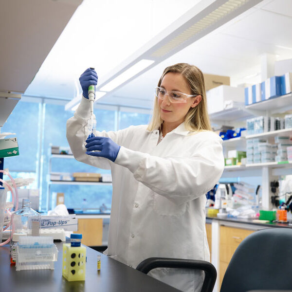 Woman using lab equipment in a lab setting studying cancer immunotherapy options