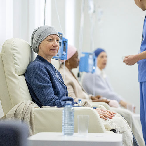 A senior woman sits in a treatment room as she receives her round of Chemotherapy.